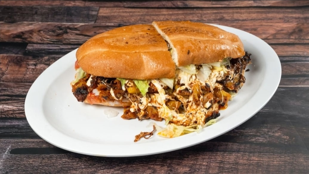Loaded torta with melted cheese at Tacos Nicole